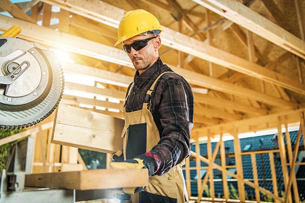 Caucasian Carpenter Worker and the Wooden House Skeleton Frame. Construction Industry Theme.