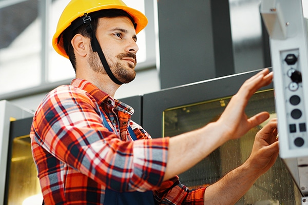 Industry Worker working on cnc machine in metal industry factory
